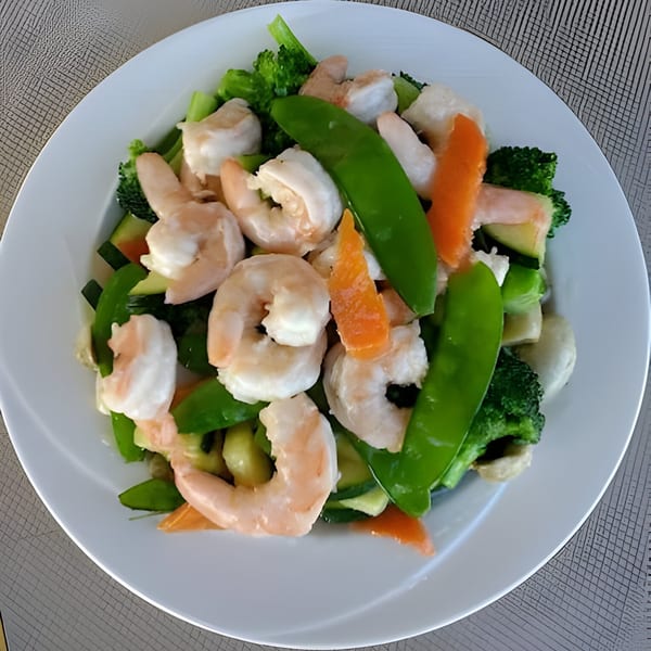 Chinnie's Kitchen shrimp and mixed vegetables, including broccoli, snap peas, and carrots, on a white plate.