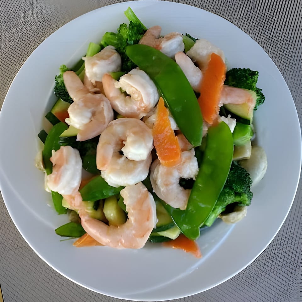 Chinnie's Kitchen shrimp and mixed vegetables, including broccoli, snap peas, and carrots, on a white plate.